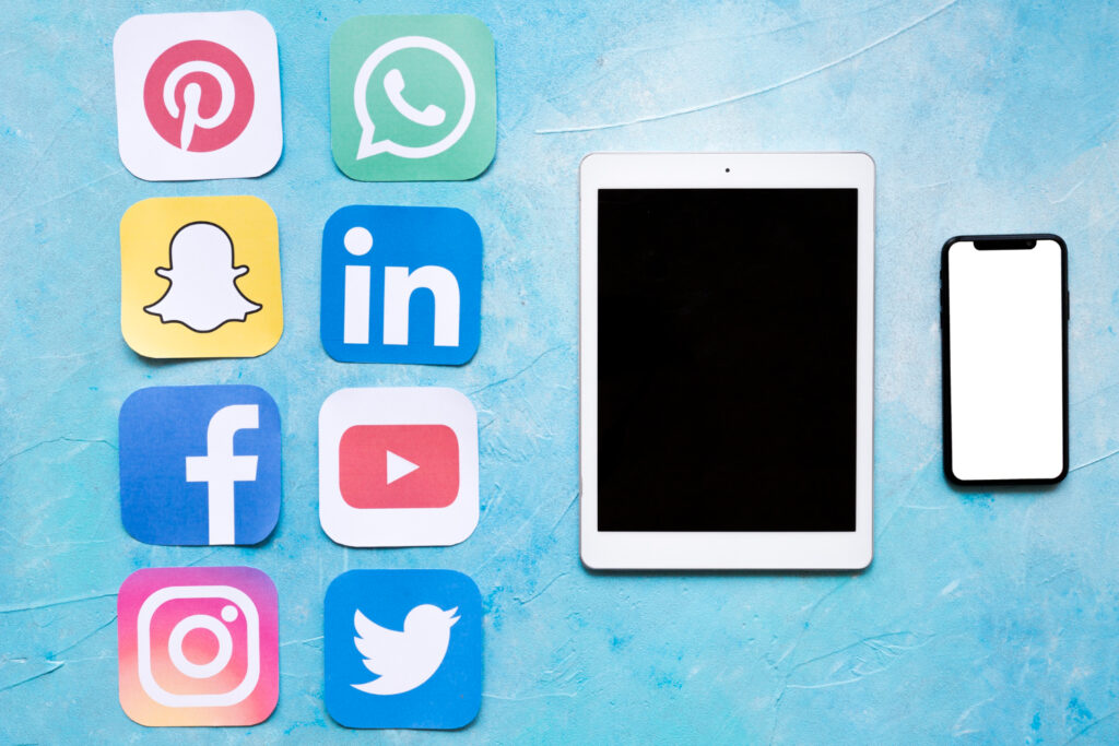 Digital tablet and mobile phone near stickers of social media icons.